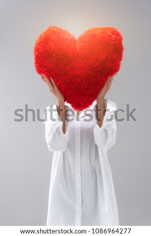 Woman in white dress embrace and hold red heart doll pillow. She smile and happy in love and valentine day or tell everybody love and take care your health.