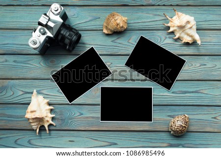 camera, seashells, photo paper with a black background on a blue wooden background. travel, resort.