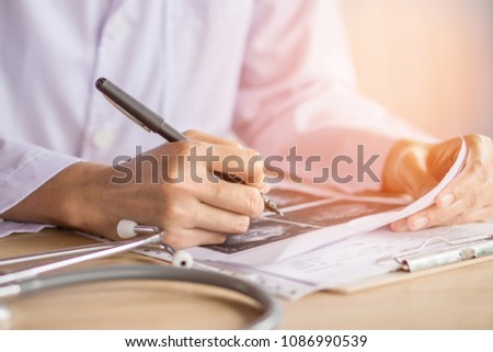 doctor working in office analyzing x-ray medical picture with stethoscope on desk 