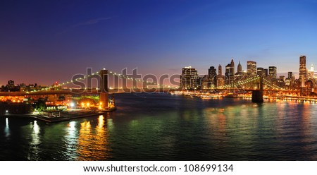New York City Manhattan downtown skyline aerial view at dusk with skyscrapers lit over East River with reflections.