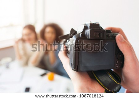 Close up of camera that is ready to take a picture of two beautiful girls. Somebody's hands are hold it.