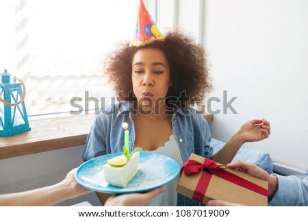A picture of birthday girl blowing up the candle and getting a present from her friends.
