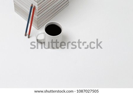 Pile Of Reading Books With color pencils on white background. directly above view of a white mug filled with black coffee.
