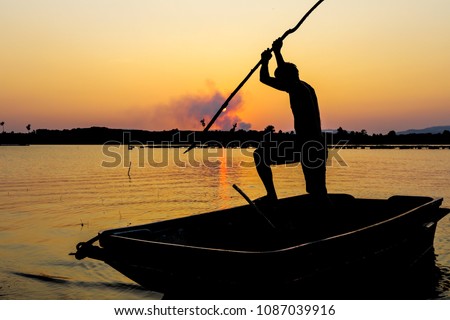 Fisherman catching the fish by spear in silhouette picture style