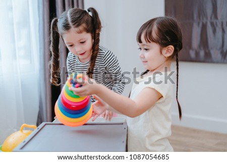 Children grils play a toy games in the room, Kids playing together with circular loop tower preschool and kindergarten education at home.