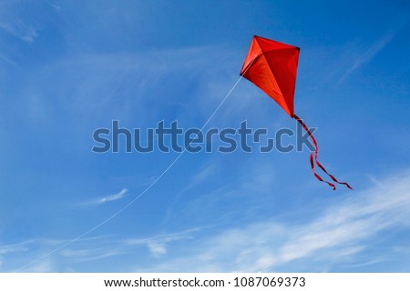 A red kite flying against a blue sky. Royalty-Free Stock Photo #1087069373