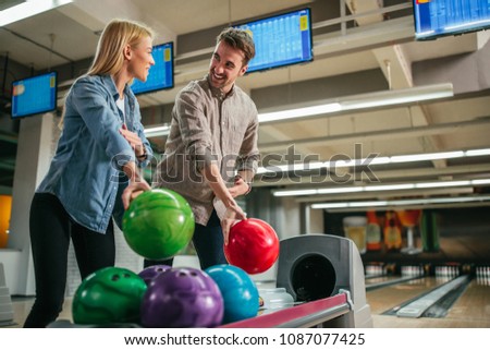 Shot of a young man explaining to his girlfriend how to hold a bowling ball