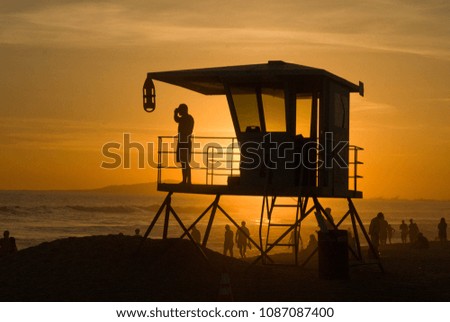 A lifeguard stands guard while the California sun sets over the Pacific
