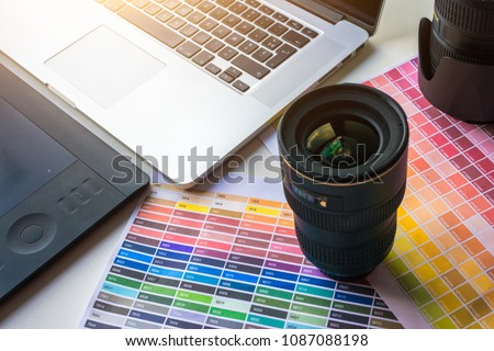 Graphist designer photographer desk with color chart, lens, laptop, digital tablet and light