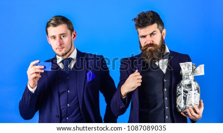 Men in suit, businessmen with jar full of cash and credit card, blue background. Finance consultant concept. Banker, finance manager recommends to his client put money on bank account