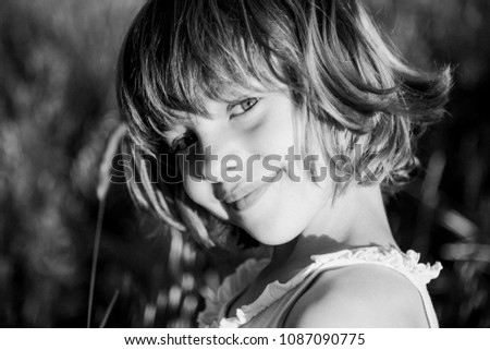 portrait outdoors at sunset of a beautiful kid girl among the flowers. Black and white photography. Innocence and children lifestyle. Summer