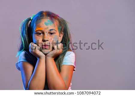 Schoolgirl has paint spots on face. Children and creativity concept
