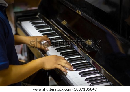 Close up side view of man hands playing piano with blurry background.