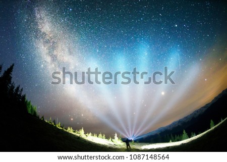 The dark mountain night shines with millions of stars over the fabulous Alpine peak in the Carpathians, the Milky Way of the Galaxy passes over a coniferous forest with a huge arc