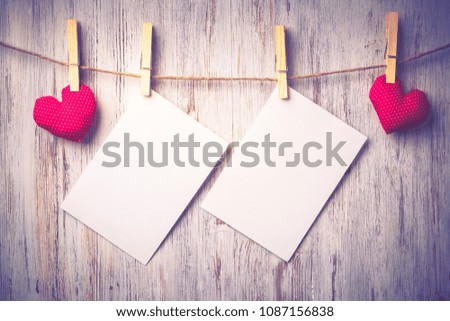 Blank sheet of paper hand made heart pinned to rope on wooden background