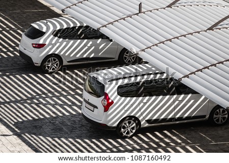 white clean cars on a parking lot in sunny summer day. the shadows from the canopy falling on vehicles Royalty-Free Stock Photo #1087160492