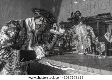 Actors in steam punk masks and antique costumes indoor. Black-white photo.