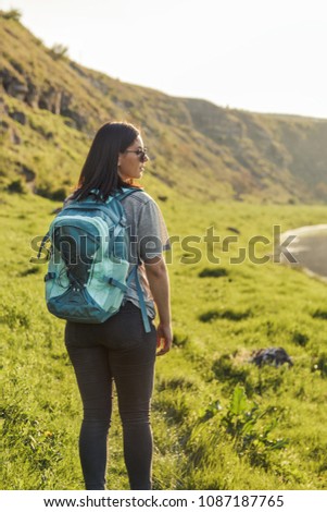 Traveler Woman with backpack looking landscape view at nature green field at sunset, tourism concept