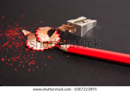 red pencil with pencil shavings and pencil sharpener up close