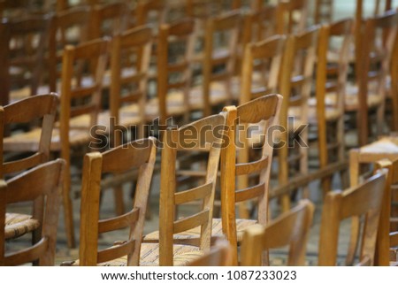 Pattern of brown wooden chairs in a french church. Group of seats rows in the interior of a religious edifice. Abstract image with multiple similar objects. Vintage design with classic shapes.