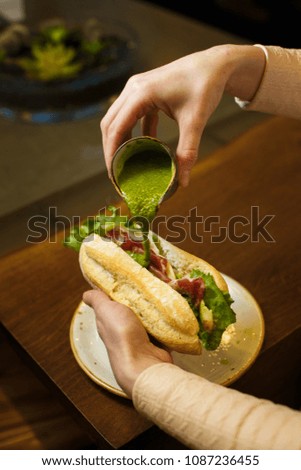 the cook pours sandwich with pesto sauce
