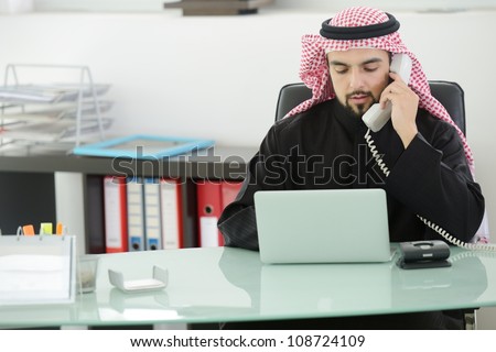 Portrait of a smart arabic business man using laptop and talking  on the phone