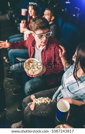 Vertical picture of guy talking to girl He is apologizing for popcorn that was spilled on girl's pants and legs. She is holding her hands on his shoulder.