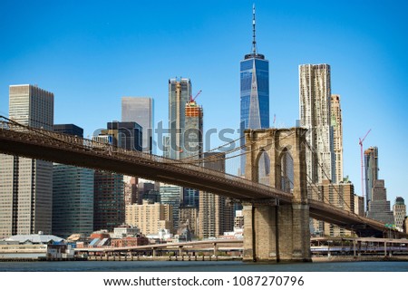 Manhattan skyline with the Brooklyn bridge and the One World Trade Center in the background during a sunny day in New York, USA.