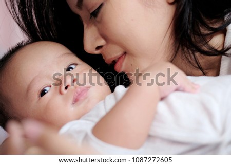 Happy smile young mother playing with little baby on bed