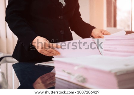 Asian business woman office workers holding are arranging documents of unfinished documents on office desk,Stack of business paper,document management,Businesswoman examining documents