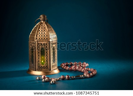 A golden Ramadhan lamp with Islamic rosary beads on dark background. Ramadan - an important Islamic festival. Islamic festive greeting card photo. Royalty-Free Stock Photo #1087345751