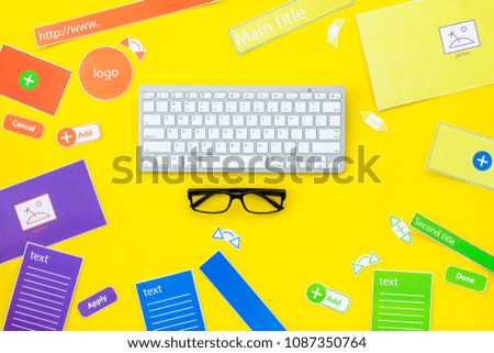 Workdesk of web site designer. Elements, blocks, instruments for make site near computer keyboard on yellow background top view