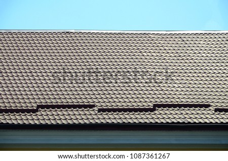 A fragment of a roof from a metal tile of dark red color. Quality Roofing