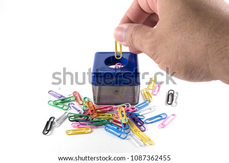 The hand is picking paper clips put Magnetic box  for put paper clips and Paper Clips colorful on white background isolated