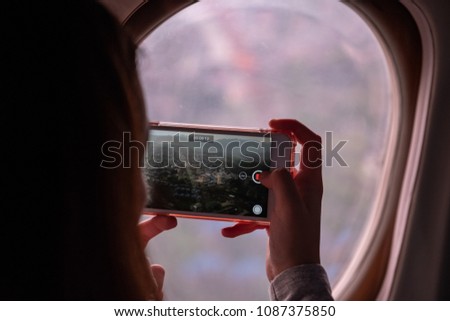 Passenger taking a photo with smartphone through the airplane window