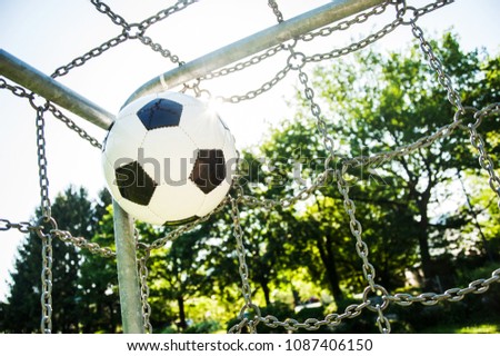football in top corner of the goal in summer with sun and lensflare