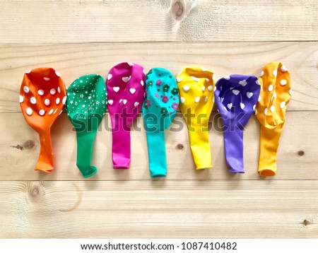 A pile of multi-color unblown rubber balloon  on wooden board background. The concept of Birthday party accessories,decoration,celebration. Top view with Selective focus.