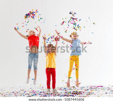 happy children on holidays have fun and  jumping in multicolored confetti on white background
