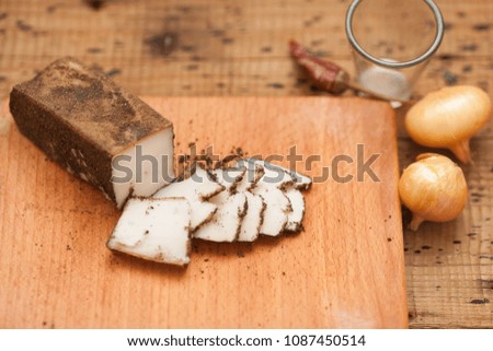 Pieces of salted lard, garlic, black pepper and onion on cutting board on wooden table. Top view
