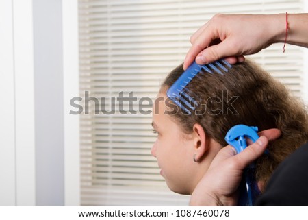 the hairdresser combs the child and moisturizes the hair with a spray of water