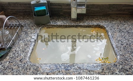 Overflowing kitchen sink, clogged drain. Plumbing problems. Royalty-Free Stock Photo #1087461236