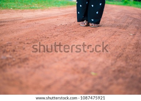 picture of a girl's feet together on a path, picture has shallow depth of field. trouser has love shapes on it, she is wearing a slippers