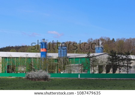 Farm buildings among the fields. Factory located in the natural landscape. Technical buildings near the forest and fields. Harvesting.