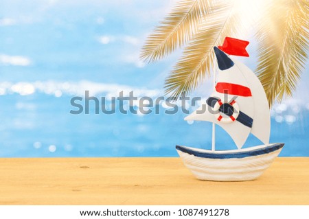 vacation and summer image with boat over wooden table and sea landscape