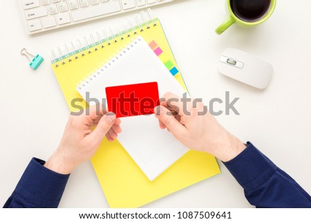 white Desk, guy holding a business card,  yellow notebook, white background with copy space, for advertisement, top view