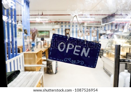Signage and text OPEN on blue board and blurred cafe or restaurant background. Concept of sign, symbol and interior decoration in house or shop.