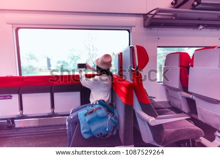 Happy moment of young woman relaxing in train seat while using smartphone and taking photo during traveling on railroad which enjoying view  on mobile phone, Travel lifestyle.