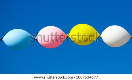 Multicolored festive balloons against the blue sky .