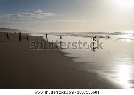 children play on the beach with village in the background