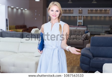 Saleswoman is demonstrating prices for sofa in store. 
